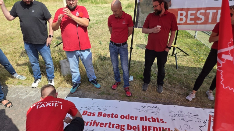 Unterschriften für den Tarifvertrag. Auch die Mitglieder des Ortsvorstands unterschrieben auf dem Banner. 